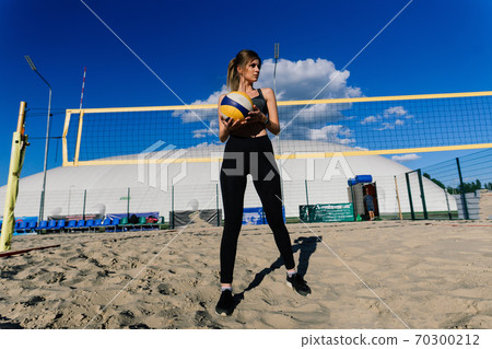 A female beach volleyball athlete with ball on the volleyball court A female beach volleyball athlete with ball on the volleyball court 70300212