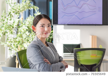 A business woman who is active in an office by a bright window 70305649