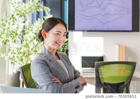 A business woman who is active in an office by a bright window 70305651