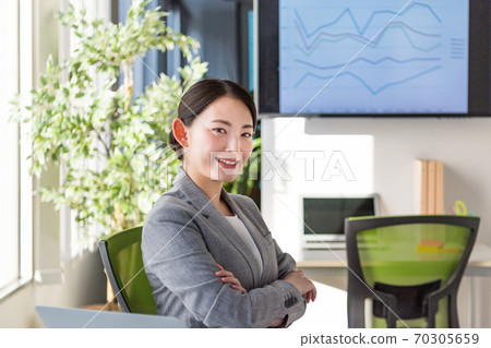 A business woman who is active in an office by a bright window A business woman who is active in an office by a bright window 70305659