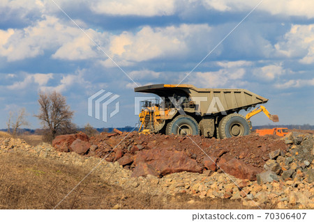 Huge yellow mining dump truck working in iron ore quarry. Mining industry Huge yellow mining dump truck working in iron ore quarry. Mining industry 70306407