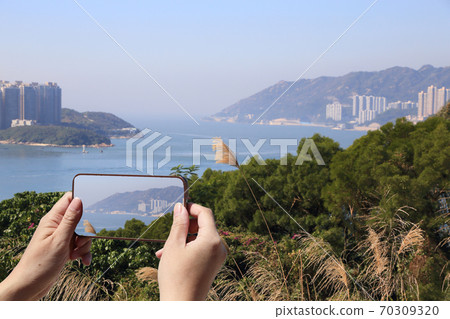 tourist taking picture of coastal landscape in Hong Kong  70309320