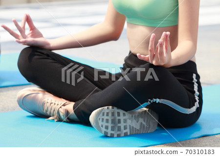Woman in sportwear practicing yoga pose outdoor, under light with shadow 70310183