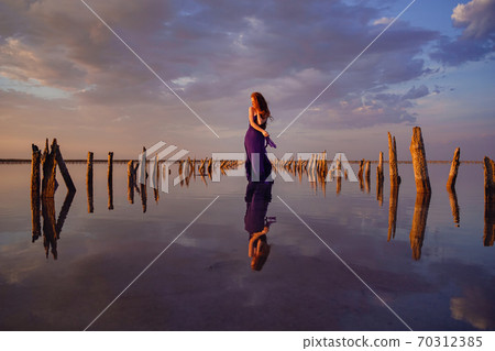 Elegant woman in silky dress walking by a salt lake. Elegant woman in silky dress walking by a salt lake. 70312385
