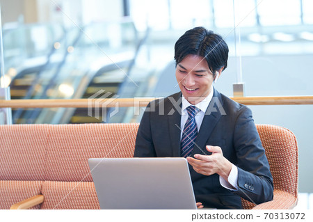 Young businessman sitting on the sofa and having an online meeting 70313072