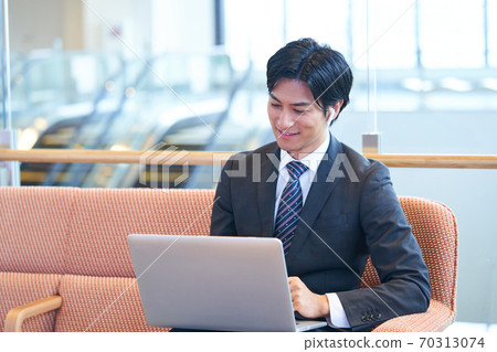 Young businessman sitting on the sofa and having an online meeting 70313074
