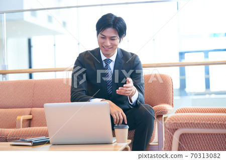Young businessman sitting on the sofa and having an online meeting 70313082