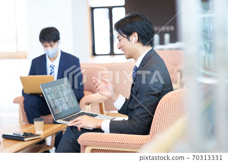 Young businessman sitting on the sofa and having an online meeting Young businessman sitting on the sofa and having an online meeting 70313331