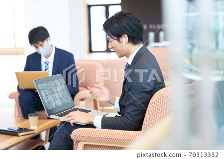 Young businessman sitting on the sofa and having an online meeting Young businessman sitting on the sofa and having an online meeting 70313332