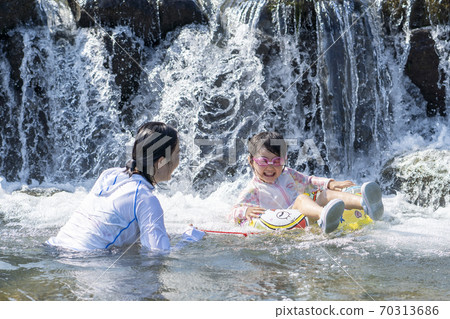 Parents and daughters playing in the river 70313686