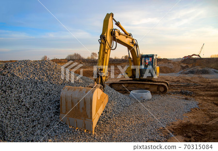 Excavator during earthmoving work at open-pit mining on blue sky background. Excavator during earthmoving work at open-pit mining on blue sky background. 70315084
