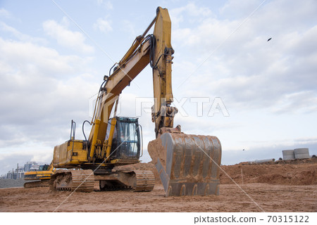 Yellow excavator during earthworks at construction site.  70315122