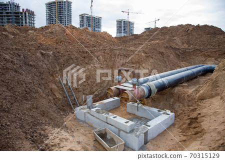 Laying heating pipes in a trench at construction site. Laying heating pipes in a trench at construction site. 70315129