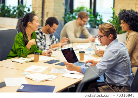 Business meeting. Group of multiracial people sitting at the desk in the modern coworking space or office and working on project together Business meeting. Group of multiracial people sitting at the desk in the modern coworking space or office and working on project together 70316945