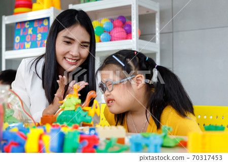 Asian girl with Down's syndrome play toy with her teacher in classroom. Concept disabled kid learning. 70317453