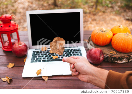 Orange pumpkin and leaves near laptop computer on a table. Autumn season time 70317589
