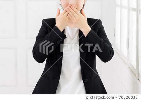 Young business woman who hides her mouth Young business woman who hides her mouth 70320033
