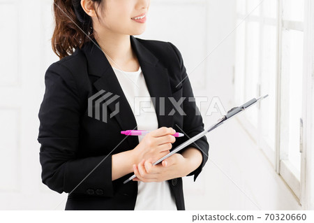 Young business woman writing notes on the clipboard 70320660