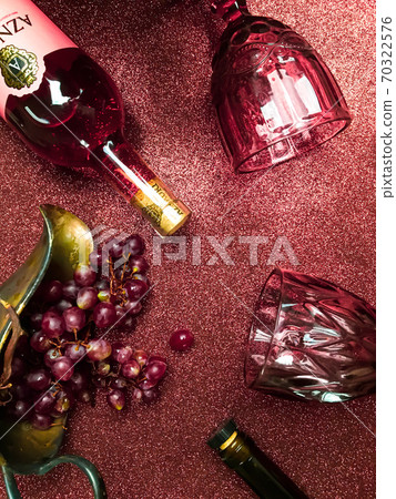 Rose wine bottle on the table, a couple of glasses and a beautiful cat Rose wine bottle on the table, a couple of glasses and a beautiful cat 70322576