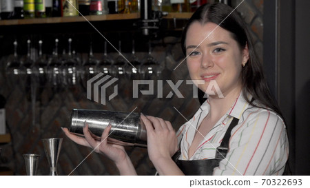 Cheerful female bartender preparing a drink for a customer Cheerful female bartender preparing a drink for a customer 70322693