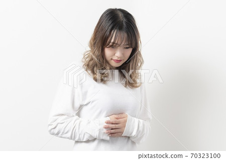 年輕女子將她的手放在她的肚子上 年輕女子將她的手放在她的肚子上 70323100