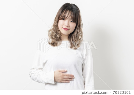 年輕女子將她的手放在她的肚子上 年輕女子將她的手放在她的肚子上 70323101