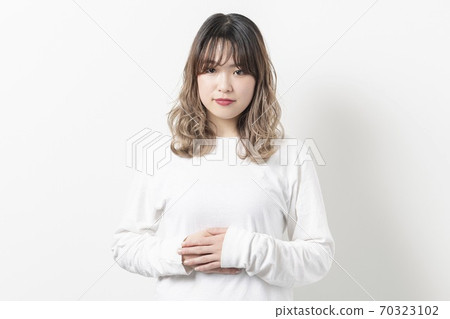 年輕女子將她的手放在她的肚子上 年輕女子將她的手放在她的肚子上 70323102