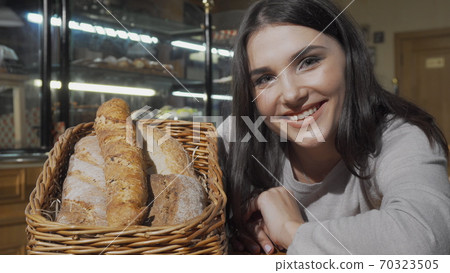 Happy young woman smiling to the camera after smelling aromatic fresh bread Happy young woman smiling to the camera after smelling aromatic fresh bread 70323505