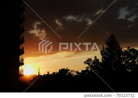 Sunset dyed in orange and silhouette of the balcony of the apartment 70323732
