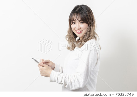 A young woman using a smartphone 70323749
