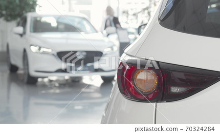 Woman getting in a new car at dealership salon on background Woman getting in a new car at dealership salon on background 70324284