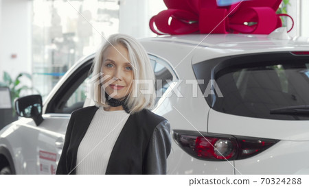 Beautiful woman smiling to the camera while choosing new automobile Beautiful woman smiling to the camera while choosing new automobile 70324288