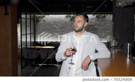 Handsome elegant young man enjoying drinking wine at the bar Handsome elegant young man enjoying drinking wine at the bar 70324809