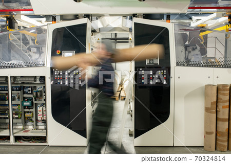 Blurred motion of male worker of contemporary factory carrying large detail 70324814