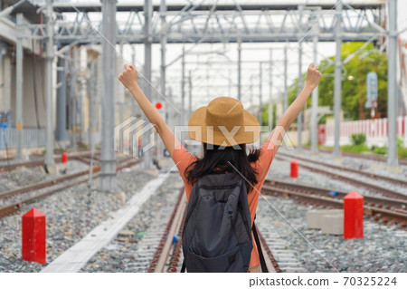 Asian woman, a tourist people, travelling in train or tram on railway with utility poles tower and cable wires in terminal station in urban city in public transportation. Asian woman, a tourist people, travelling in train or tram on railway with utility poles tower and cable wires in terminal station in urban city in public transportation. 70325224