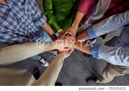 Top view of different ethnicity business people doing fists bump, celebrating success while standing in the office Top view of different ethnicity business people doing fists bump, celebrating success while standing in the office 70325632