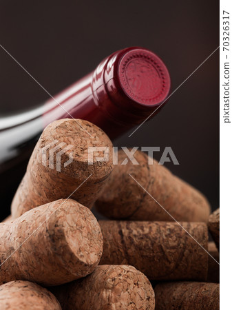Bottle of red wine on top of various wine corks. 70326317