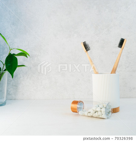 Zero waste bathroom items. Bamboo toothbrushes in recycling material holder, natural mouthwashing tabs and fresh green plants in glass. Oral care essentials. Eco-friendly home. Minimalism. Copy space. Zero waste bathroom items. Bamboo toothbrushes in recycling material holder, natural mouthwashing tabs and fresh green plants in glass. Oral care essentials. Eco-friendly home. Minimalism. Copy space. 70326398