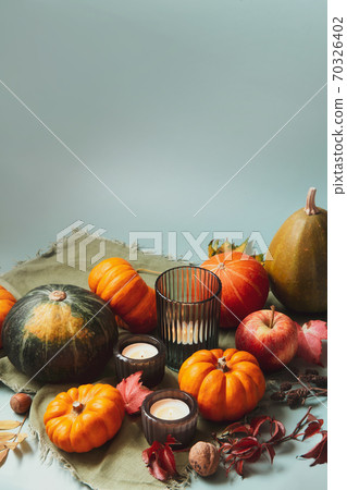 Orange, green decorative pumpkins, apples, nuts, fallen leaves and candles in autumn harvest composition on trendy earth tones background. Thanksgiving minimalism concept. Selective focus. Copy space Orange, green decorative pumpkins, apples, nuts, fallen leaves and candles in autumn harvest composition on trendy earth tones background. Thanksgiving minimalism concept. Selective focus. Copy space 70326402