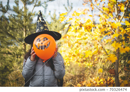 Halloween kids. Little girl with jack o' lantern in witch hat with pumpkin. Toddler kid in witch costume playing in autumn park. Halloween kids. Little girl with jack o' lantern in witch hat with pumpkin. Toddler kid in witch costume playing in autumn park. 70326474