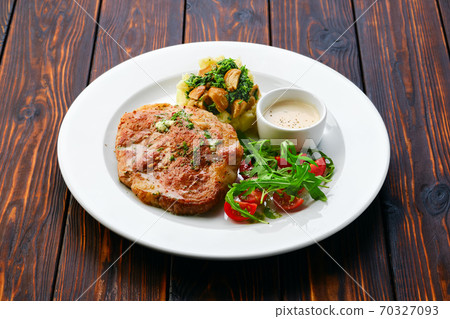 Fried chop pork cutlet with mashed potato and boletus edulis gravy served with fresh tomato cherry and arugula. Fried chop pork cutlet with mashed potato and boletus edulis gravy served with fresh tomato cherry and arugula. 70327093