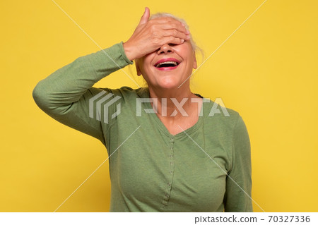 Senior beautiful woman smiling covering eyes for surprise Senior beautiful woman smiling covering eyes for surprise 70327336