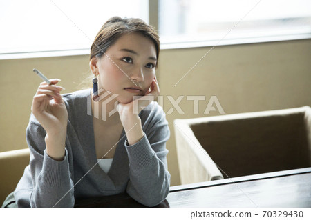 A woman smoking a cigarette 70329430