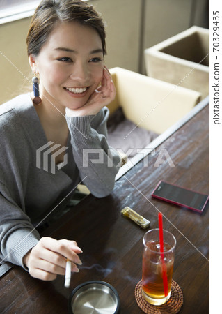 A woman smoking a cigarette 70329435