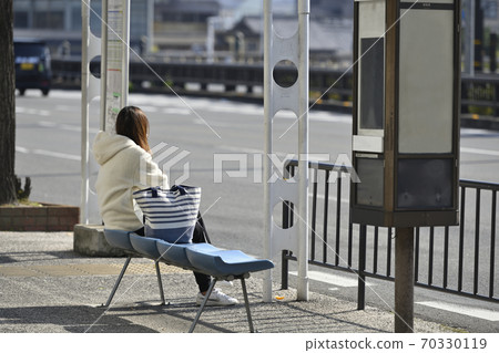等待公共汽車的婦女在公共汽車站 70330119