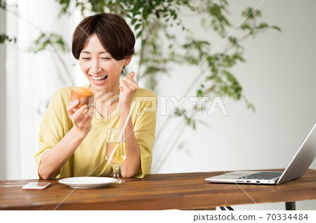 一個女人在一家咖啡館吃糖果 一個女人在一家咖啡館吃糖果 70334484