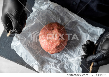 minced meat on paper, stone tray, black gloves minced meat on paper, stone tray, black gloves 70334496