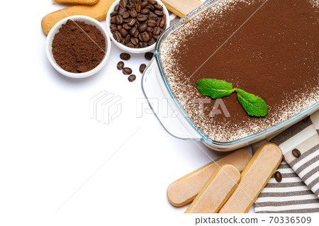 Traditional Italian Tiramisu dessert in glass baking dish and savoiardi cookies isolated on white Traditional Italian Tiramisu dessert in glass baking dish and savoiardi cookies isolated on white 70336509