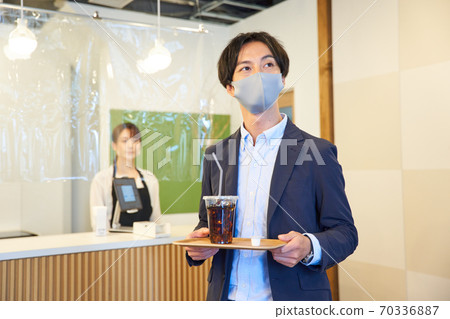 一個年輕人在一家咖啡館買冰咖啡 70336887