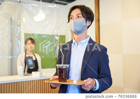 一個年輕人在一家咖啡館買冰咖啡 70336888